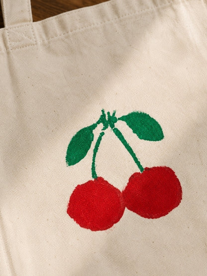 Close-up of the hand-painted cherry design showing the stencil details, canvas texture, and stitching.