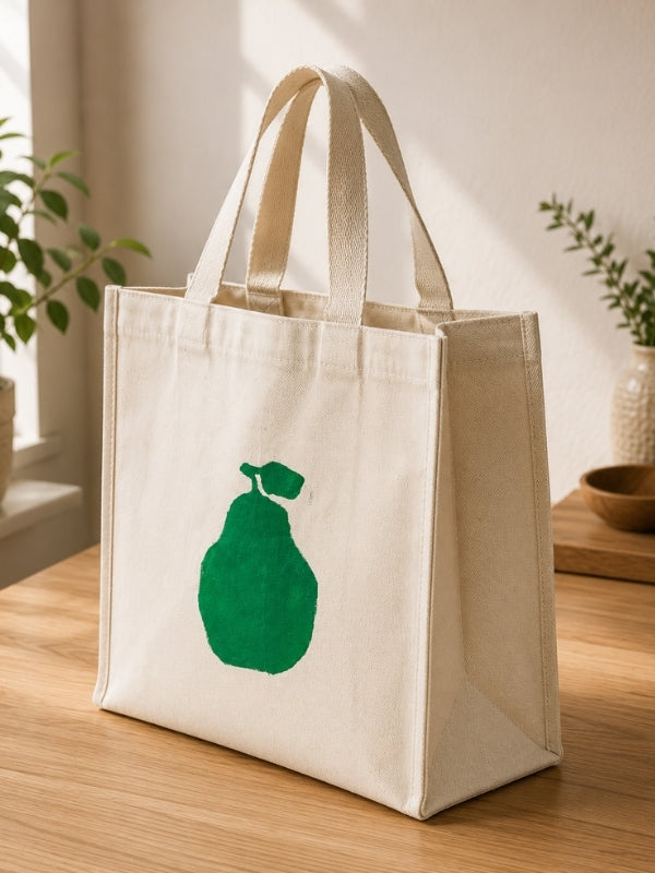  Angled view of the pear-design tote bag showing the 4-inch gusset, shoulder handles, and spacious shape.
