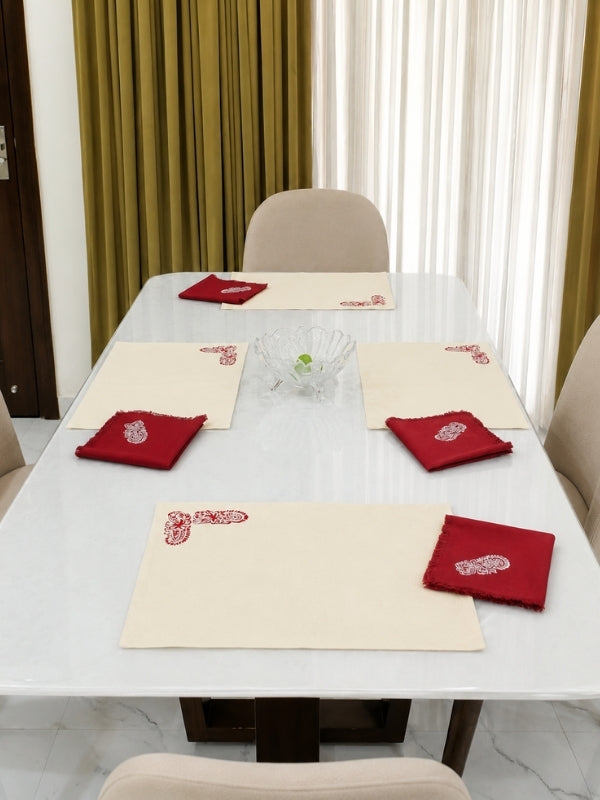 Red floral cotton table mat and matching napkin arranged on a dining table with plates and cutlery.