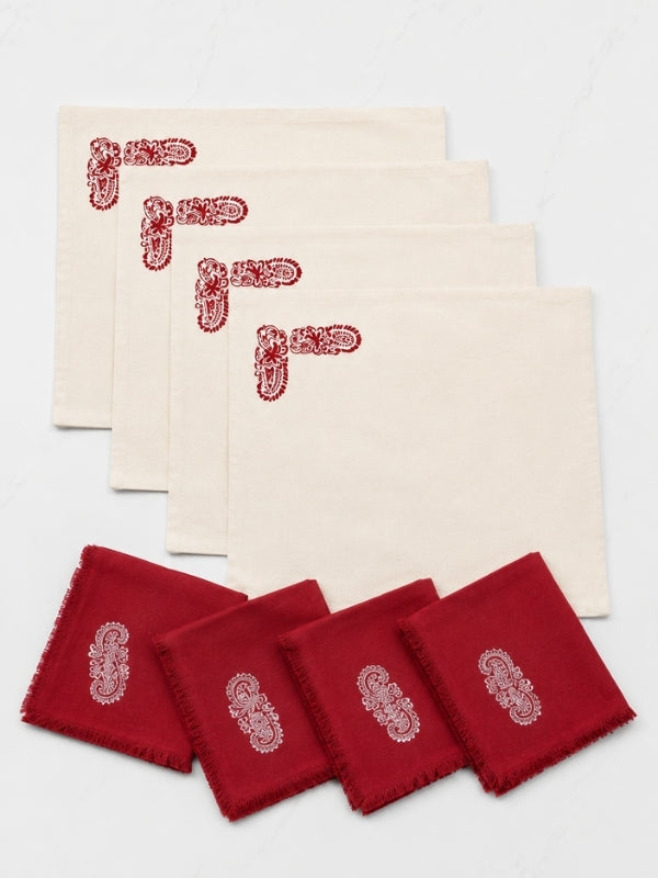 Set of four hand-painted red floral cotton table mats with four matching napkins displayed together.