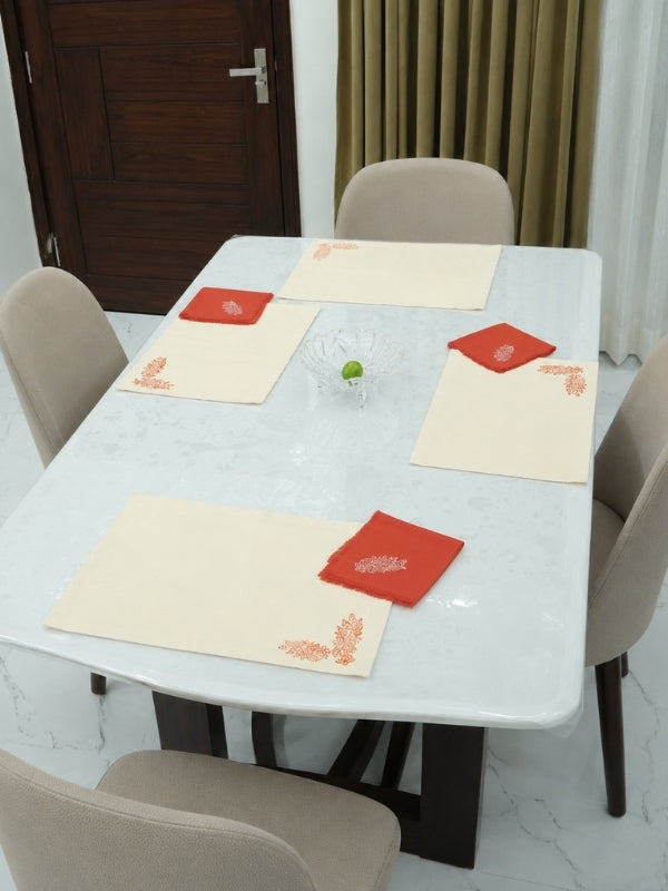 Orange floral cotton table mat and matching napkin arranged on a dining table with plates and cutlery.