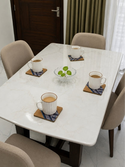 Set of handcrafted square MDF coasters placed beneath cups on a coffee table during everyday use.