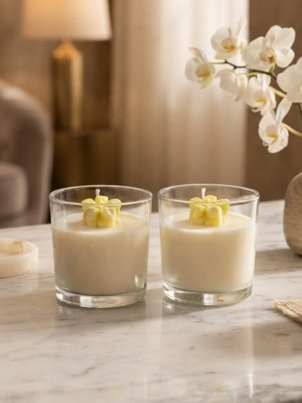 Angled view of the yellow flower soy wax candle displaying the transparent glass jar, decorative wax flower, and candle depth.
