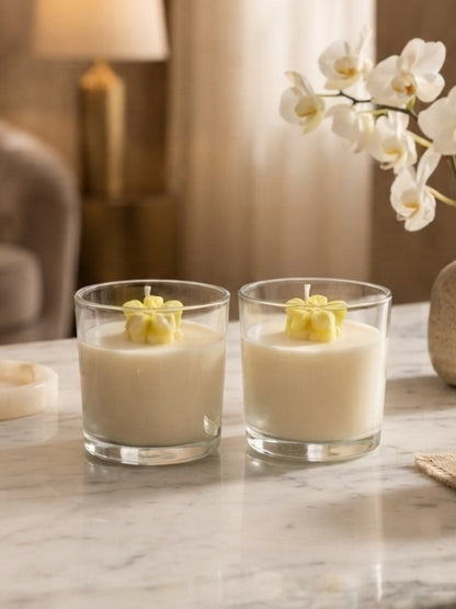 Angled view of the yellow flower soy wax candle displaying the transparent glass jar, decorative wax flower, and candle depth.