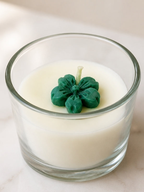 Close-up of the handcrafted soy wax candle highlighting the green wax flower decoration, smooth wax finish, and glass container.
