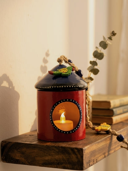 Alternate bird house tea light holder displayed on a shelf with an electric LED tea light illuminating the interior.