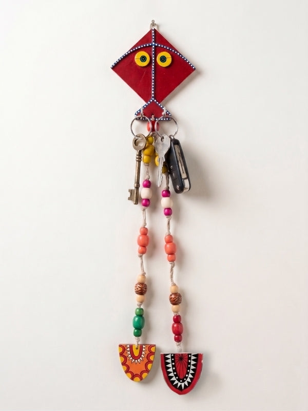 Close-up of the handcrafted kite key holder highlighting the wooden finish, bead work, and macramé detailing.
