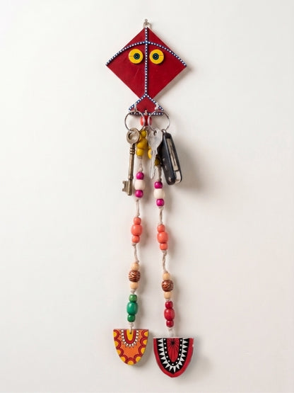 Close-up of the handcrafted kite key holder highlighting the wooden finish, bead work, and macramé detailing.
