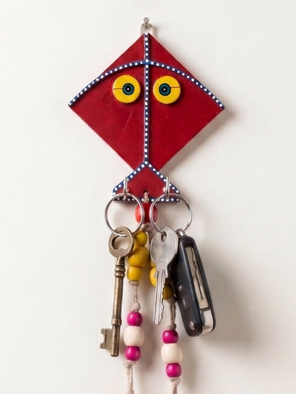 Handcrafted kite key holder displayed near a doorway with everyday keys hanging from the hooks.
