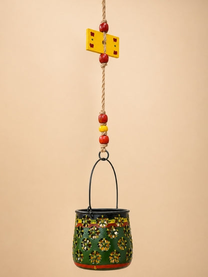 Close-up of the handcrafted metal lantern showing the floral cutwork, thick macramé knots, wooden beads, and decorative finish.