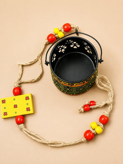 Angled view of the handcrafted metal tealight holder displaying the lantern shape, thick macramé cord, and hanging design.
