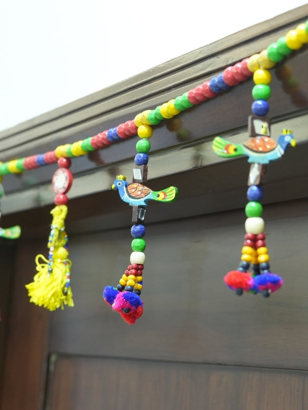 Angled view of the handcrafted peacock wall hanging showing its wooden construction and decorative artwork.
