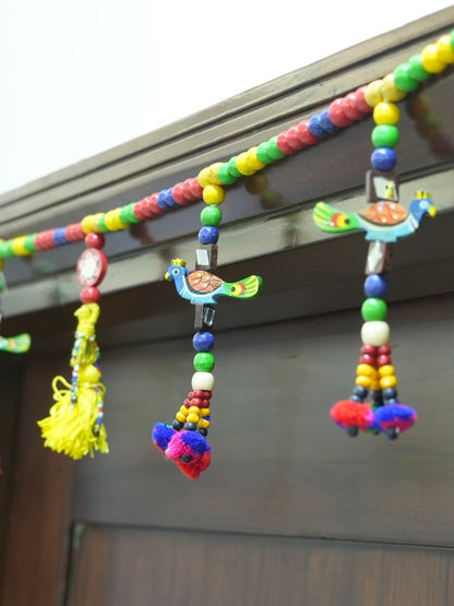 Angled view of the handcrafted peacock wall hanging showing its wooden construction and decorative artwork.
