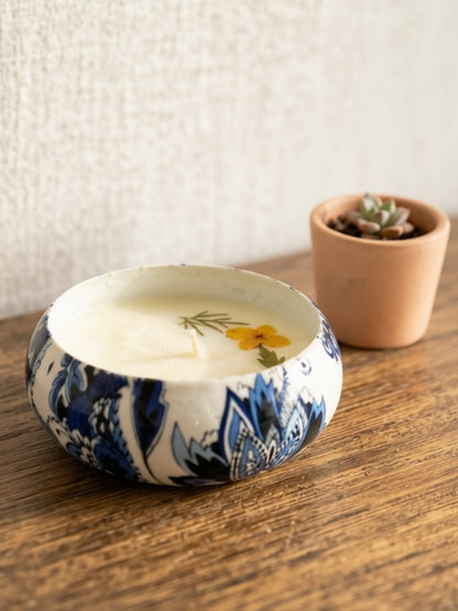 Angled view of the handcrafted botanical soy wax candle showing the floral arrangement and handcrafted finish.