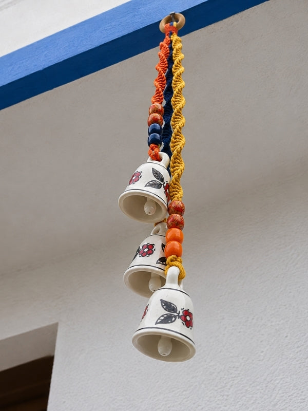 Angled view of the handcrafted triple ceramic bell hanging displaying its layered decorative structure.
