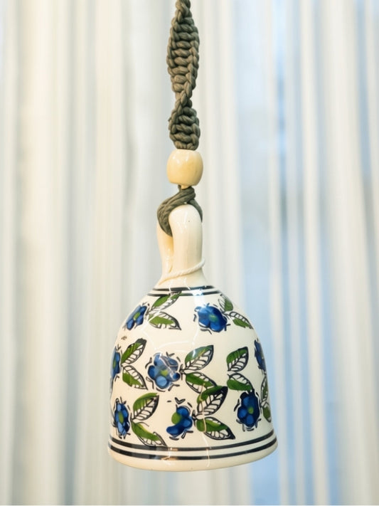 Close-up of the handcrafted ceramic bell highlighting the painted finish, wooden beads, and intricate macramé knots.
