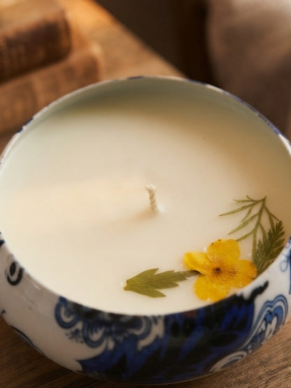 Close-up of the handcrafted soy wax candle highlighting the dried yellow flower decoration, smooth wax finish, and cotton wick.
