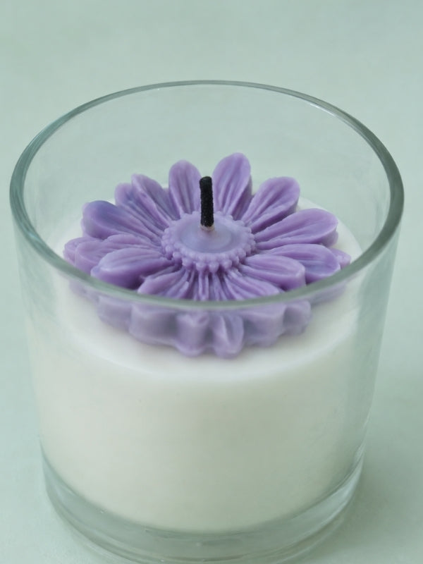 Close-up of the light purple soy wax candle highlighting the dried flower decoration, smooth wax finish, and cotton wick.