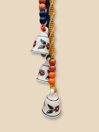Close-up of the three ceramic bells highlighting the hand-painted finish, macramé knots, and wooden bead detailing.

