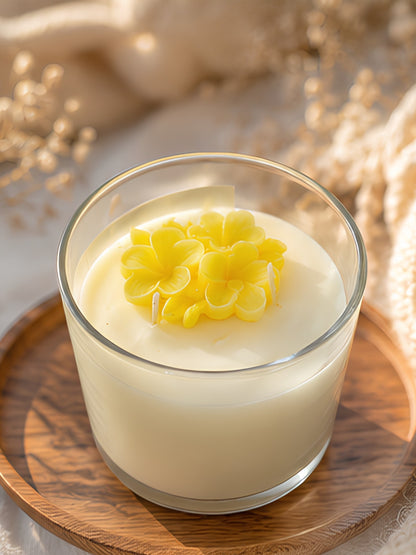 Close-up of the yellow scented soy wax candle showing the decorative wax flowers, smooth wax finish, and clear glass jar.