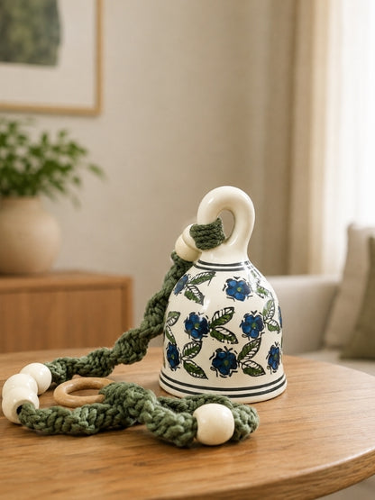 Handcrafted ceramic bell hanging measuring approximately 24 inches in length, featuring a large hand-painted ceramic bell, cotton macramé cord, and wooden bead detailing for home décor.