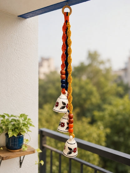 Handcrafted ceramic triple bell hanging displayed on a doorway or balcony, adding warmth and handcrafted character to the space.
