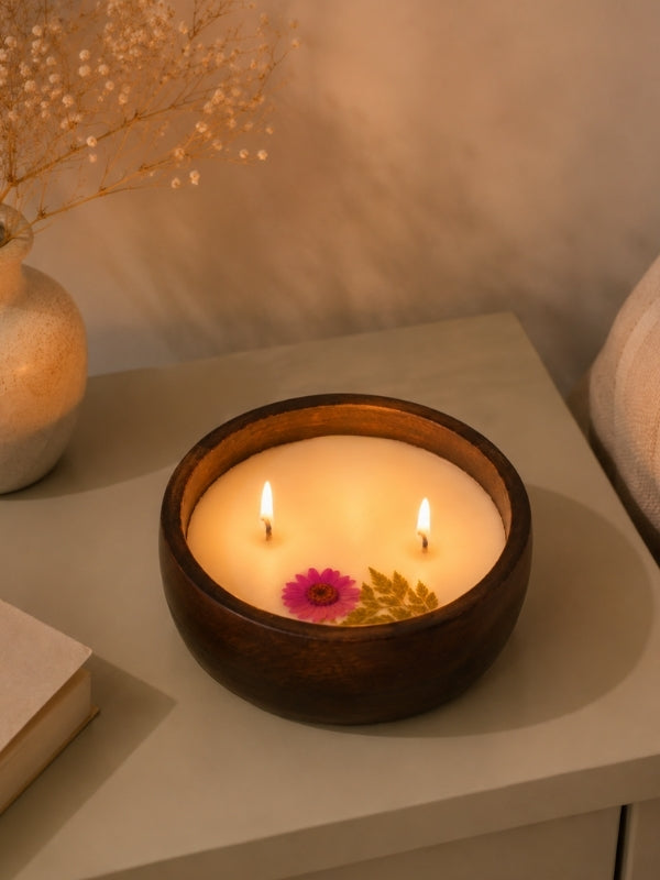 Handcrafted soy wax candle decorated with naturally dried Pink flowers displayed on a coffee table, adding warmth and handcrafted elegance to the living space.
