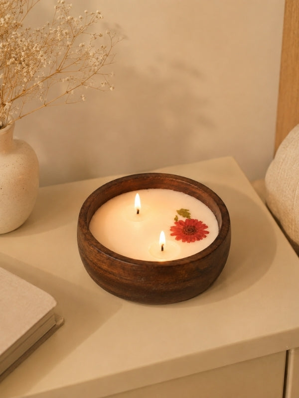 Handcrafted soy wax candle decorated with naturally dried flowers displayed on a coffee table, adding warmth and handcrafted elegance to the living space.
