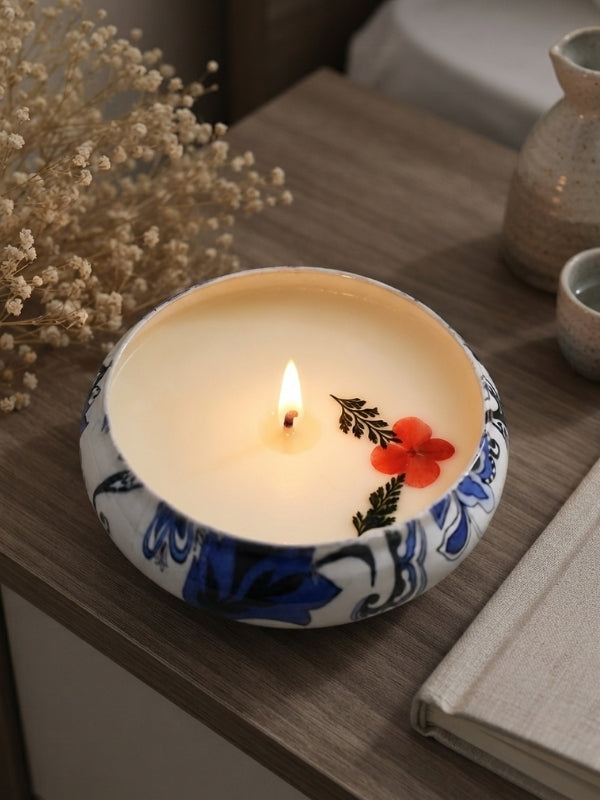 Handcrafted soy wax candle with dried flower decoration displayed on a bedside table, creating a calming decorative setting.
