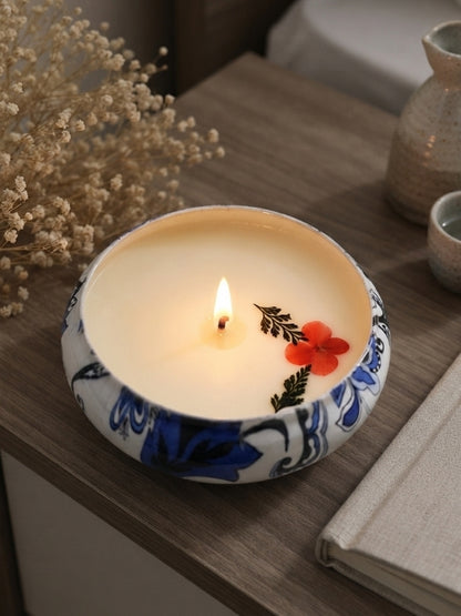 Handcrafted soy wax candle with dried flower decoration displayed on a bedside table, creating a calming decorative setting.
