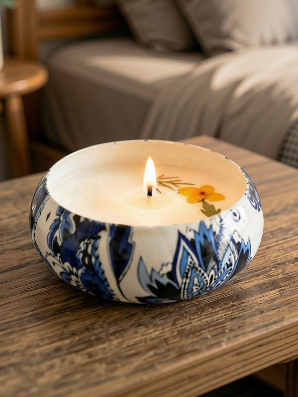 Handcrafted soy wax candle with dried flower decoration displayed on a bedside table, creating a calming decorative setting.
